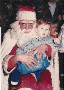 a man dressed as santa claus is holding a baby