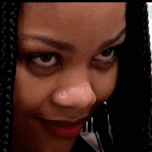 a close up of a woman 's face with braids looking at the camera .