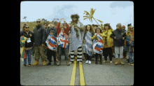 a group of people standing on the side of a road holding flags one of which says ' uk ' on it