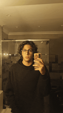 a young man taking a selfie in a bathroom mirror