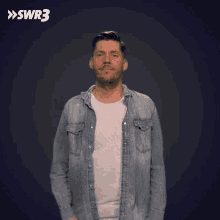 a man in a denim shirt is waving his hand in front of a blue background with swr3 written on it