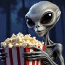 an alien is holding a bag of popcorn in his hands .