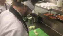 a man in a chef 's uniform is cutting onions in a kitchen with a jar of ranch dressing on the counter