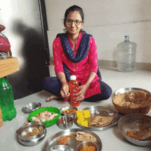 a woman sits on the floor surrounded by plates of food