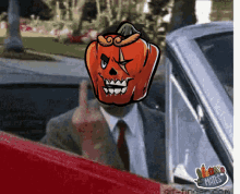 a man in a suit and tie with a pumpkin head giving the middle finger