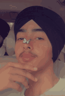 a young man wearing a turban has a butterfly on his nose