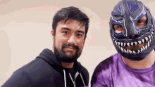 two men are posing for a picture one wearing a mask and the other wearing a purple shirt