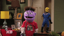 a purple puppet with a red shirt that says skull on it