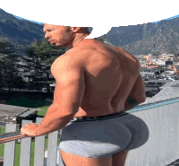 a shirtless man in boxer shorts stands on a balcony