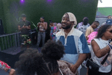 a man in a blue and white shirt is standing in a crowd