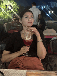 a woman is sitting at a table holding a glass of wine