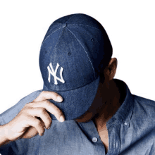 a man wearing a denim ny hat covering his face