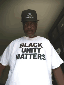 a man wears a white shirt that says black unity matters