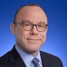 a man wearing glasses and a suit and tie is smiling .