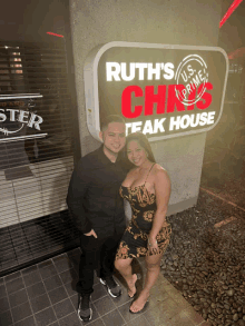 a man and a woman pose in front of ruth 's chris steak house