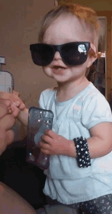 a little girl wearing sunglasses is holding a cell phone case