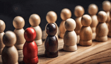 a group of wooden peg dolls are lined up on a wooden board