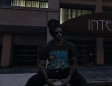 a man with dreadlocks is sitting in front of a building that says inte