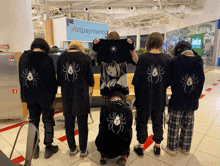 a group of people wearing black shirts with spiders on them