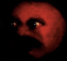 a close up of a person 's face in the dark with a glowing red eye .