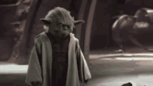 a close up of yoda from star wars standing in a dark room .