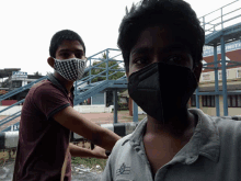 a man wearing a mask stands next to another man wearing a mask in front of a sign that says aisha