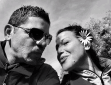 a black and white photo of a man and a woman with a flower in their hair