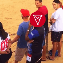 a group of people standing on a beach with a red circle with a triangle in it