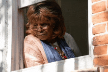 a woman with glasses looks out a window