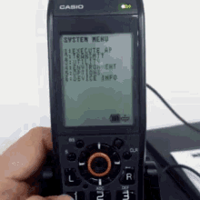 a person is holding a casio phone with the system menu displayed on the screen