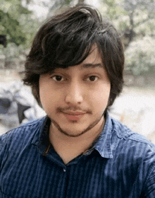 a young man with a beard wearing a blue shirt