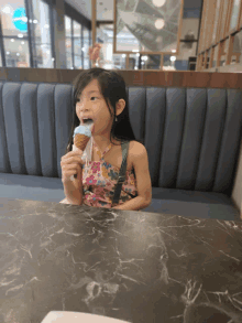 a little girl is eating an ice cream cone in a restaurant