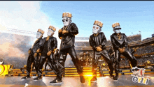 a group of men wearing masks are dancing in a stadium .