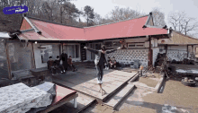 a man stands on a wooden platform in front of a house with a blue sign that says twinkle map