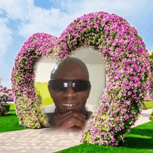 a picture of a man in sunglasses is framed by a heart shaped flower arrangement