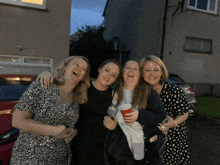 four women are posing for a picture and one of them is holding a red cup