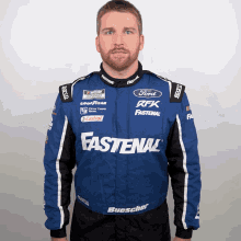 a man wearing a blue fastenal jacket poses for a photo