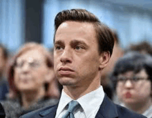 a man in a suit and tie is standing in front of a crowd .