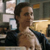 a woman holds a baby in her arms and looks at the camera
