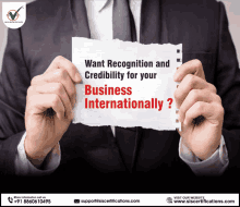 a man in a suit holds a piece of paper that says want recognition and credibility for your business internationally