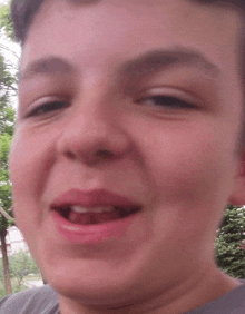 a close up of a boy 's face with a gray shirt on