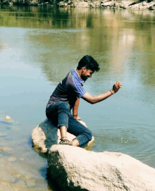 a man is sitting on a rock in the water