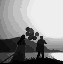 a bride and groom are holding balloons in a black and white photo