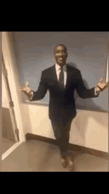 a man in a suit and tie stands in a hallway with his arms outstretched