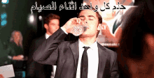 a man in a suit and tie is drinking water