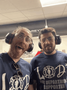 two men wearing ear muffs and t-shirts that say fire department supporter