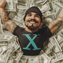 a man is laying in a pile of money and his shirt says x