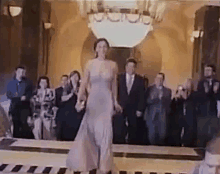 a woman in a purple dress is walking down a runway in front of a group of people .