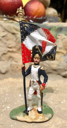 a figurine of a soldier holding a flag is standing on a table .