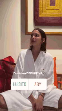 a woman in a bathrobe sits on a couch with a sticker that says luisito